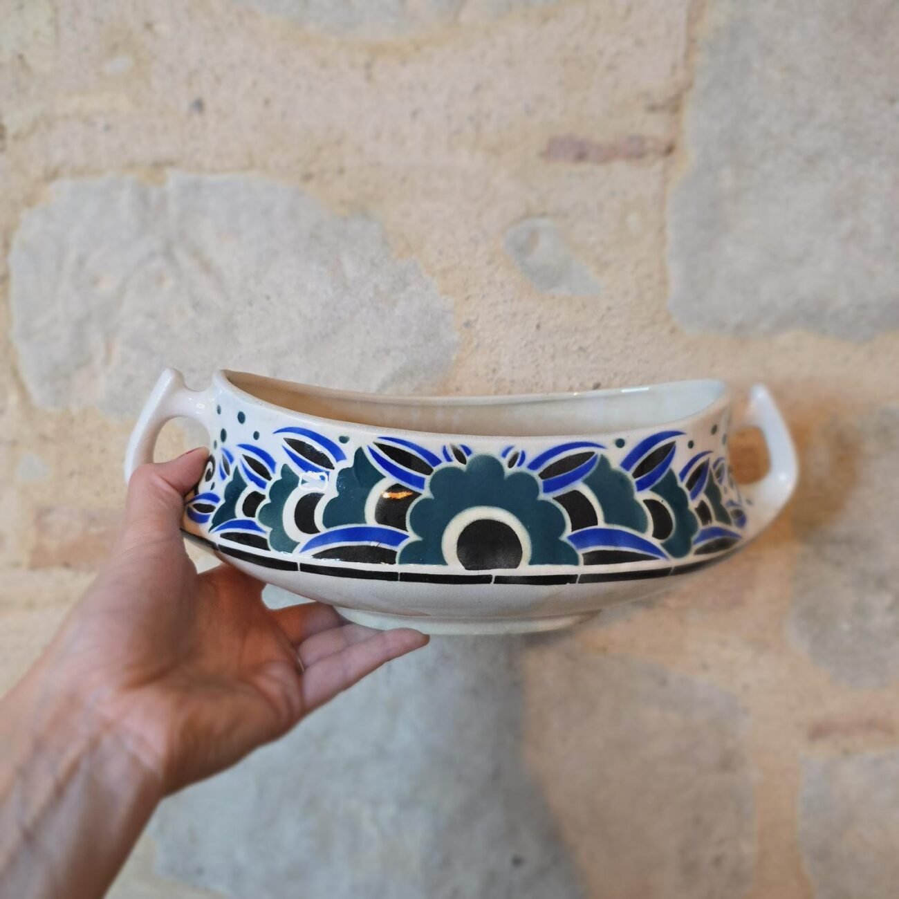 Motif floral sur fond crème, vue rapprochée du côté de la jardinière vintage.
