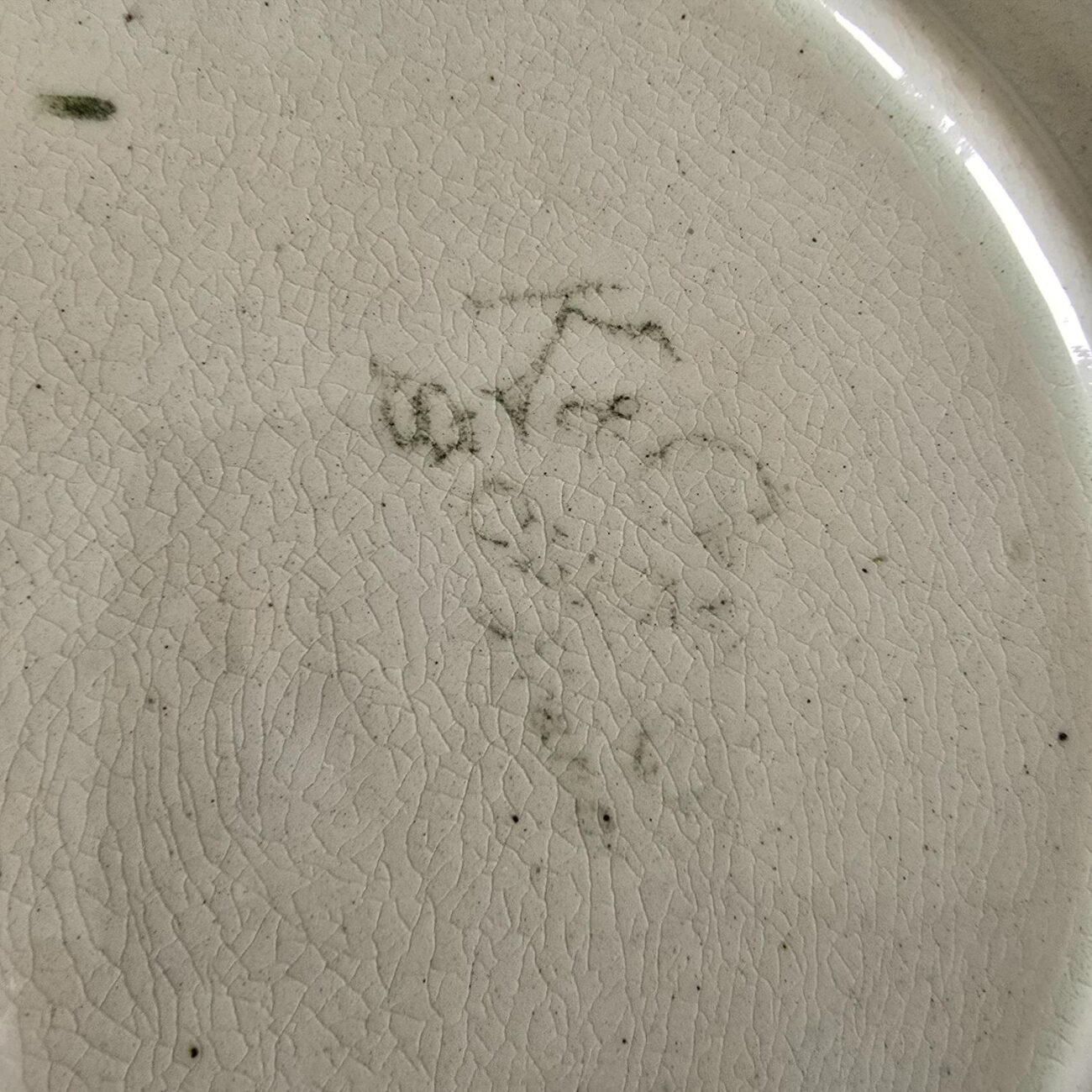 Détail du dos de l’assiette St Clément, signature KG estompée visible sur faïence ancienne craquelée