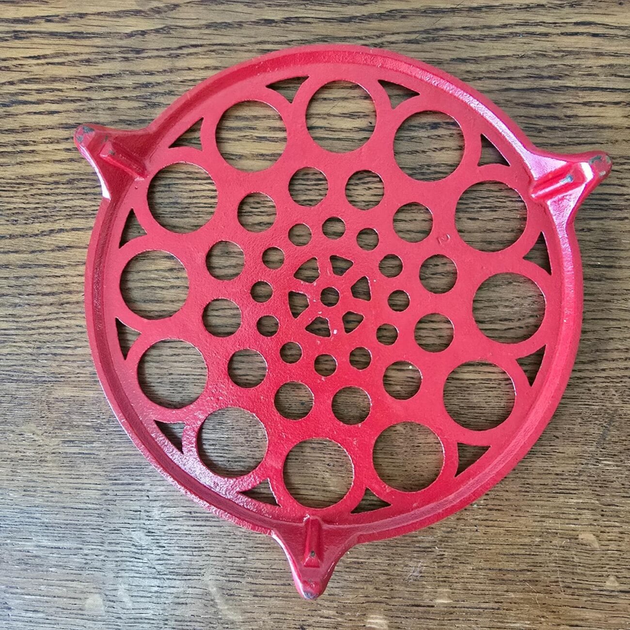 Vue rapprochée du dessous de plat en fonte émaillée rouge, design bulles années 70 – objet vintage pour décoration cuisine