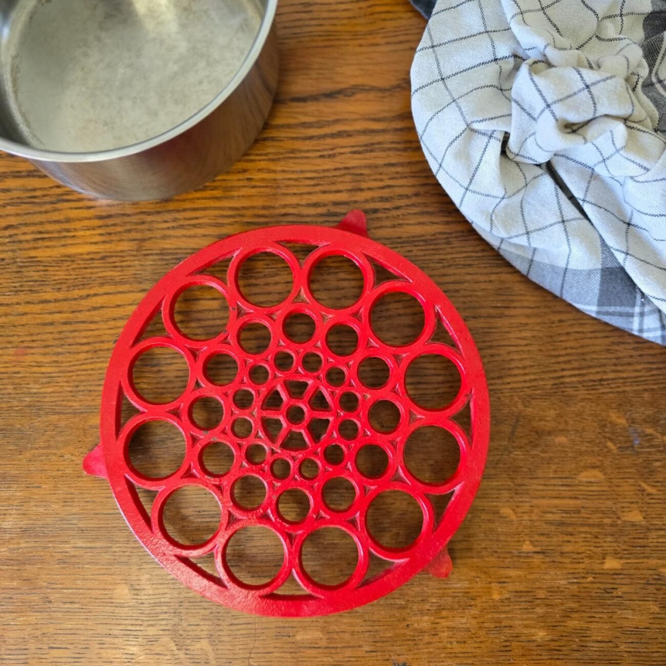Vue de dessus du dessous de plat rond en fonte rouge, avec patine visible – accessoire vintage pour décoration de cuisine