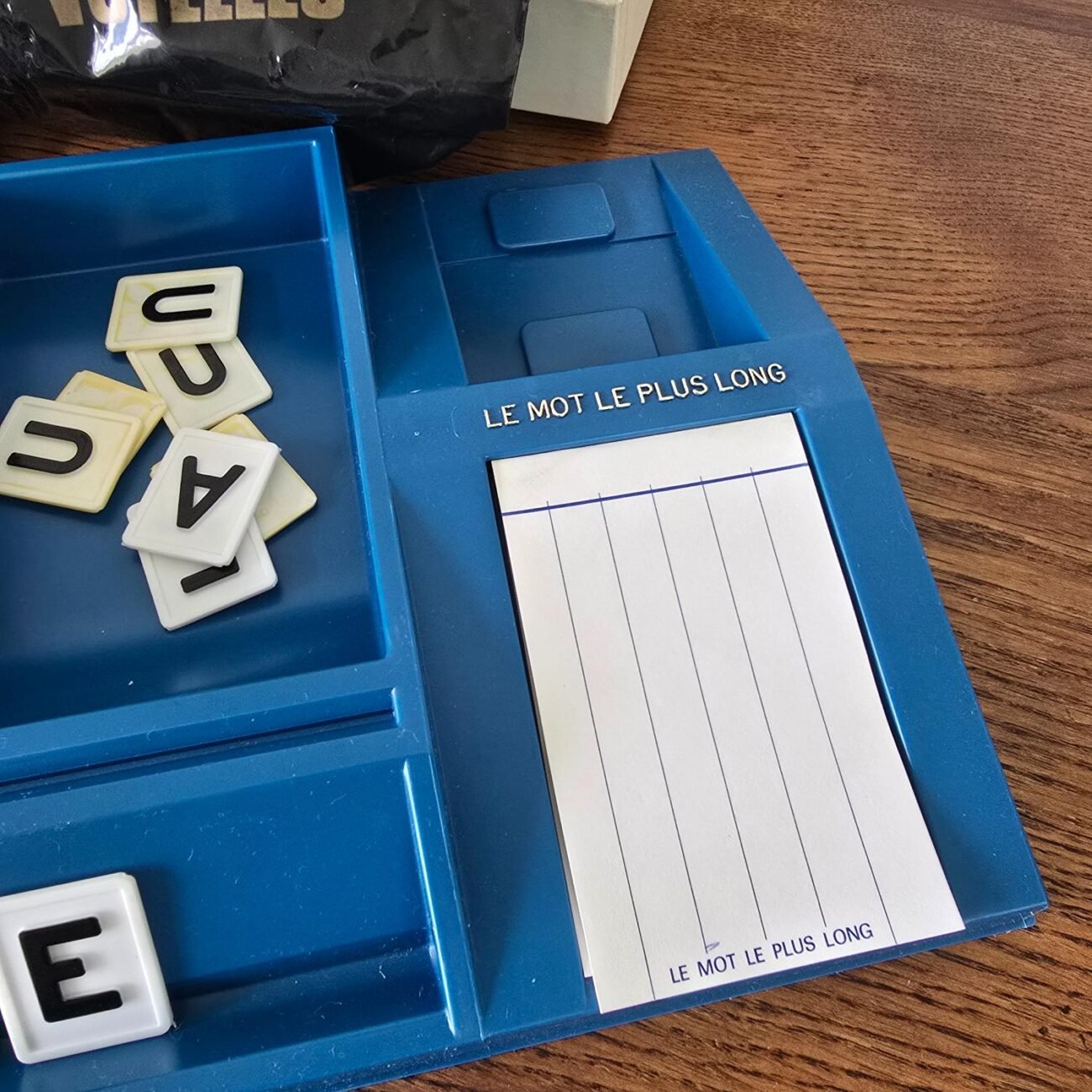 Focus sur le plateau de jeu en plastique avec compartiments et bloc de scores.