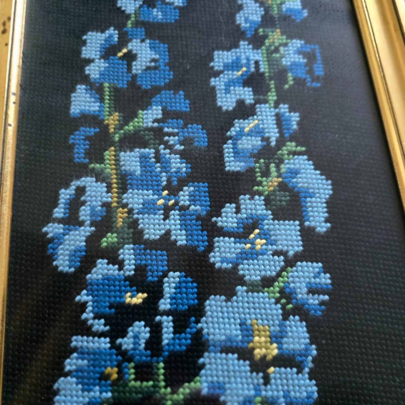 Gros plan sur les fleurs bleues brodées en point de croix sur toile noire