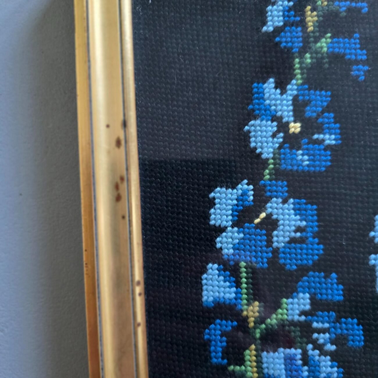 Gros plan sur les fleurs bleues brodées en point de croix sur toile noire