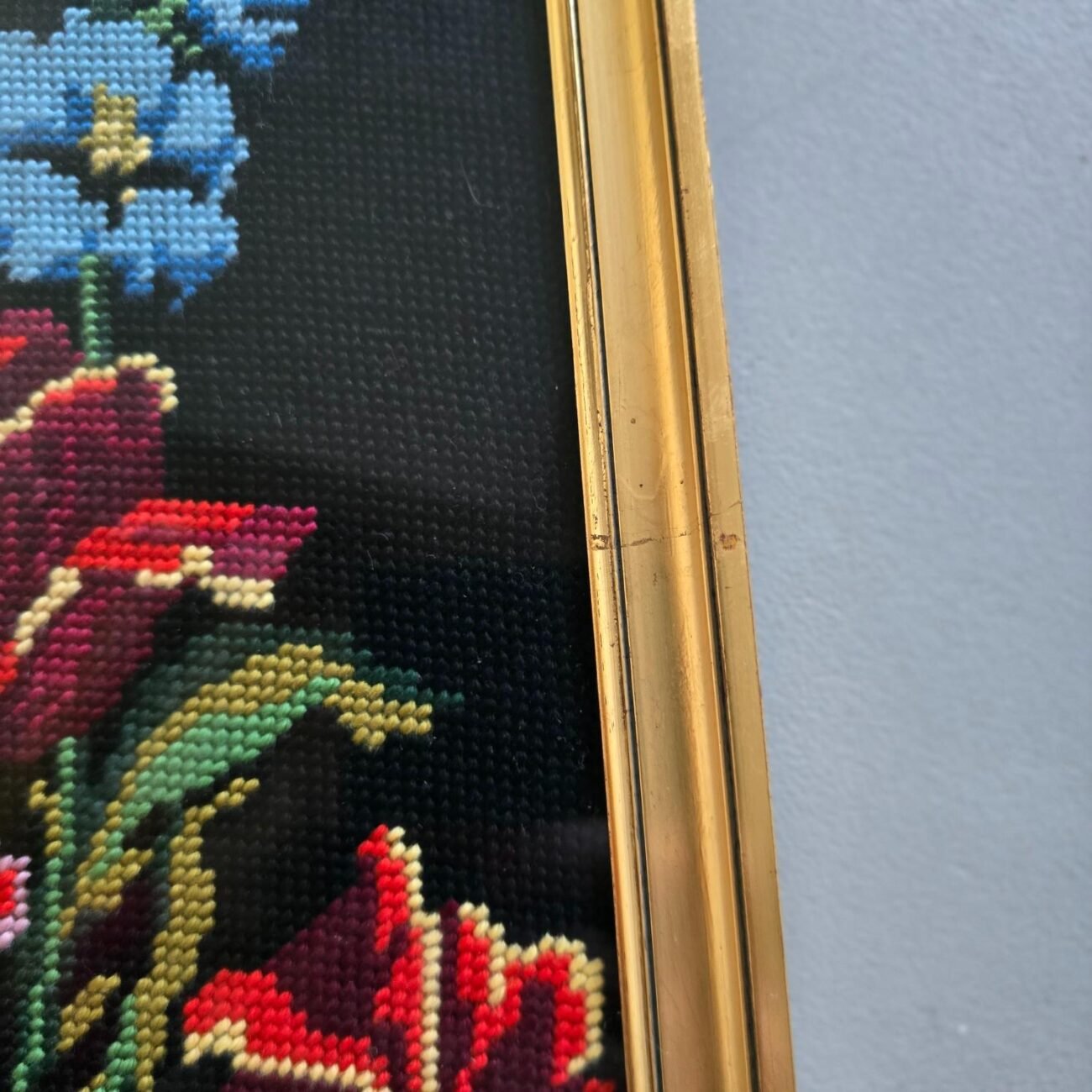 Zoom sur la base du canevas avec tulipes rouges et tiges vertes – broderie vintage
