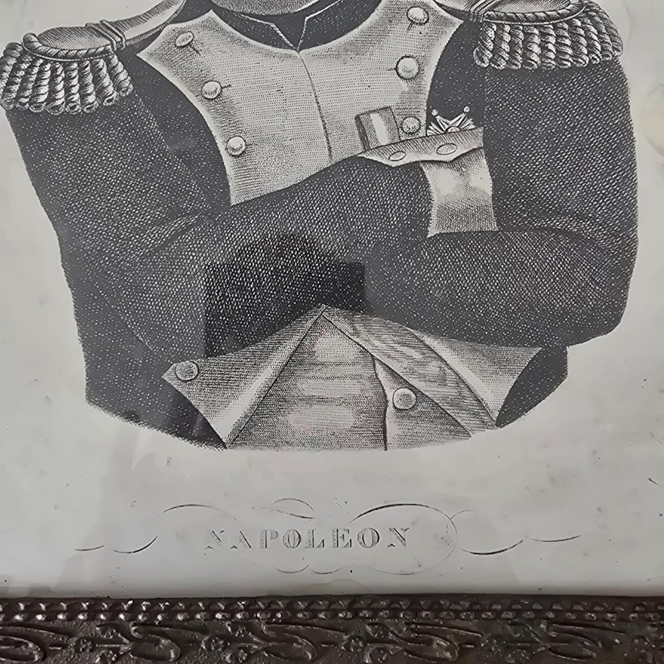Zoom sur le bas du portrait avec l’inscription gravée « NAPOLEON » en lettres capitales.