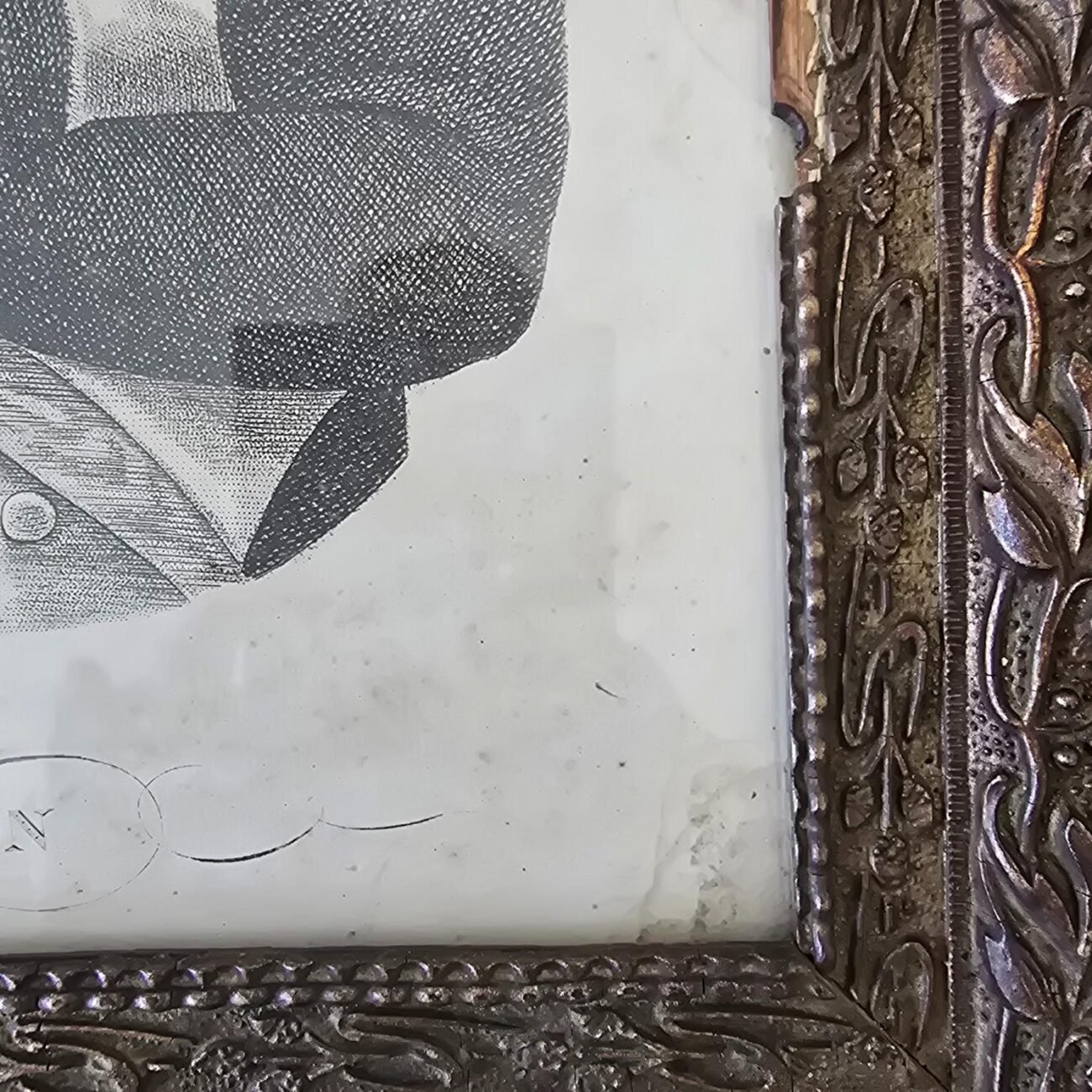 Gros plan sur l’angle inférieur droit du cadre, montrant les motifs sculptés et les manques de matière.