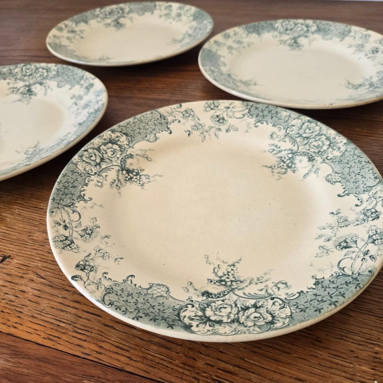 Vue de profil des 4 assiettes anciennes sur table en bois