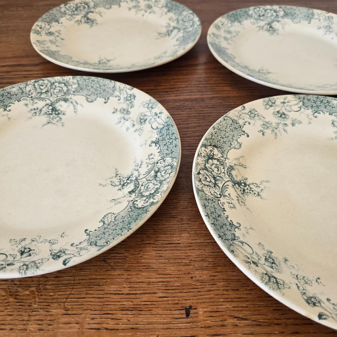 Autre vue de profil des 4 assiettes anciennes sur table en bois