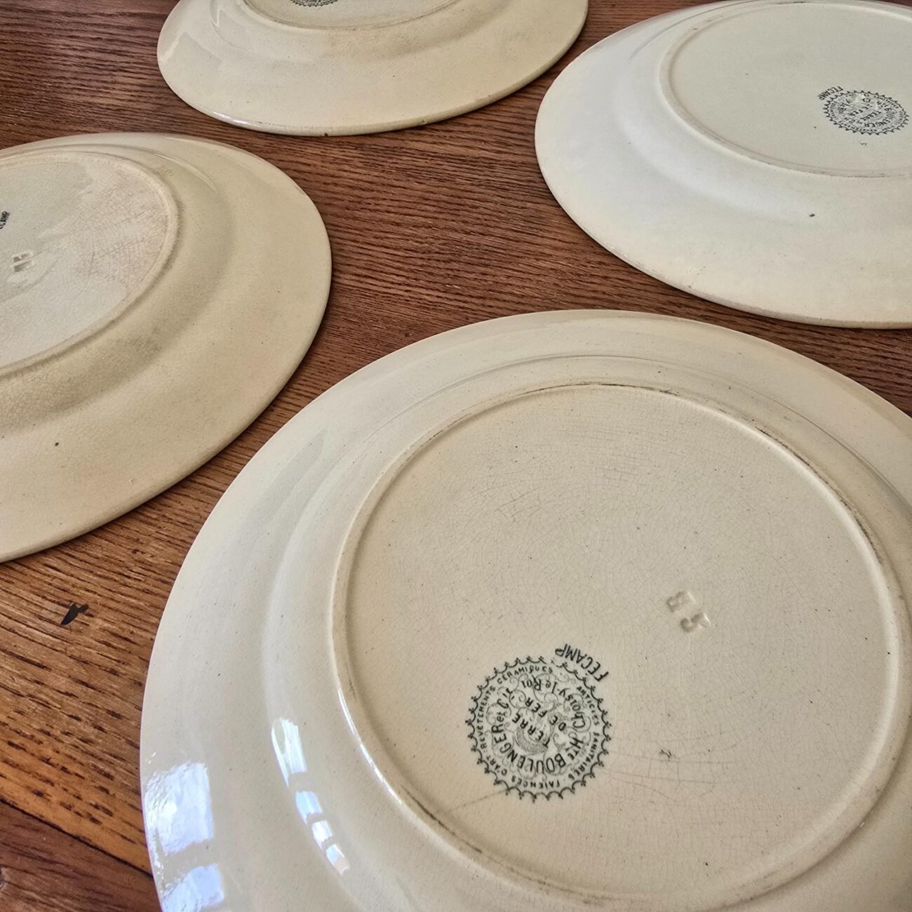 Vue de profil du dos des 4 assiettes anciennes sur table en bois