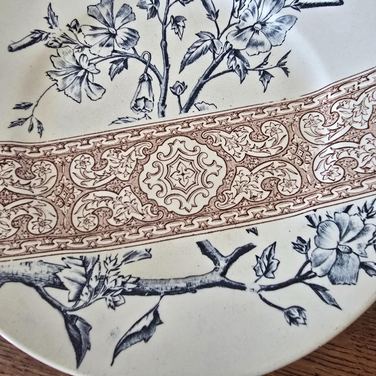Zoom sur une assiette ancienne Longchamp terre de fer décor bleu et frise brune.